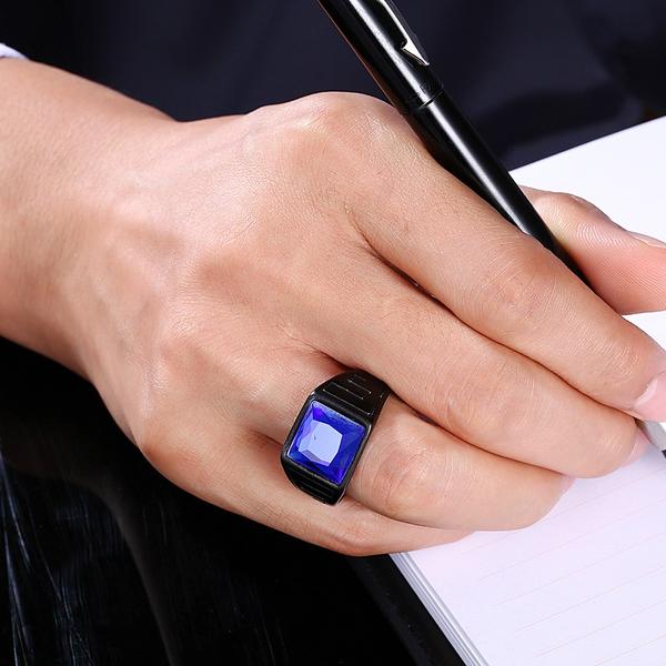 Hand wearing a black ring with a blue gemstone writing in a notebook showcasing rings as messengers of Love