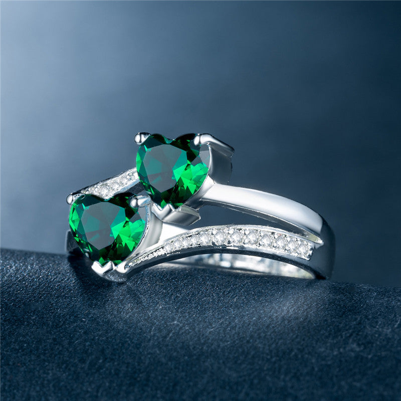 affordable luxury rings for women with two heart-shaped green gemstones and diamond accents