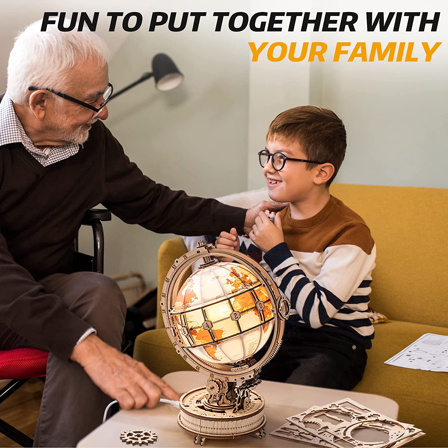 Grandfather and grandson assembling a 3D wooden globe model kit together at home