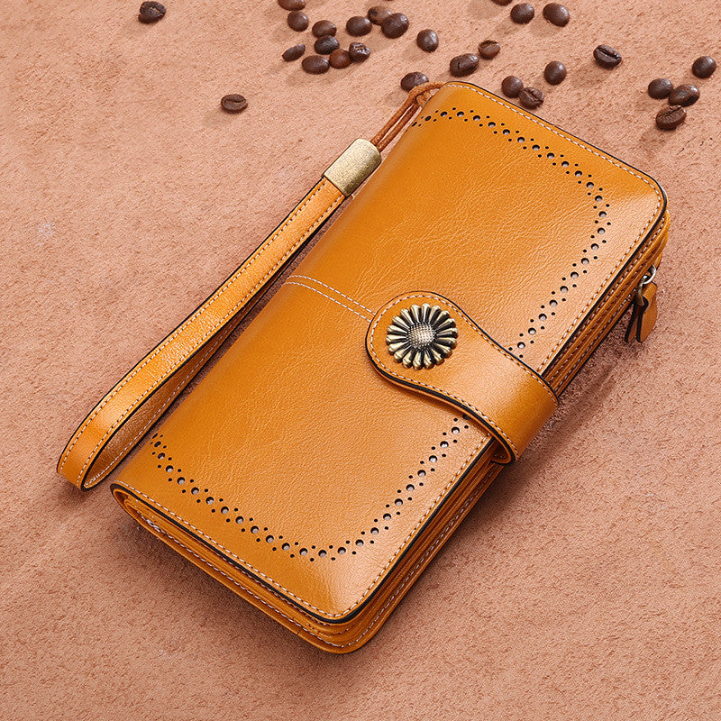 Elegant leather wallet for women in tan brown with wrist strap and decorative button closure