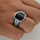 men's elegant black gemstone ring with silver detailing worn on finger