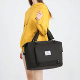 black compact work backpack for women carried by model in yellow hoodie with top handles