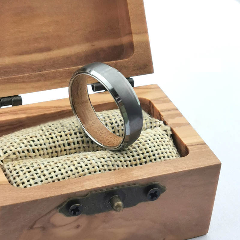Men's silver tungsten carbide ring displayed in a wooden box with a textured interior