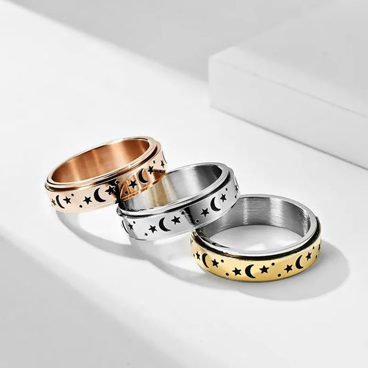 Three stainless steel star spinner rings in gold, silver, and rose gold with moon and star designs