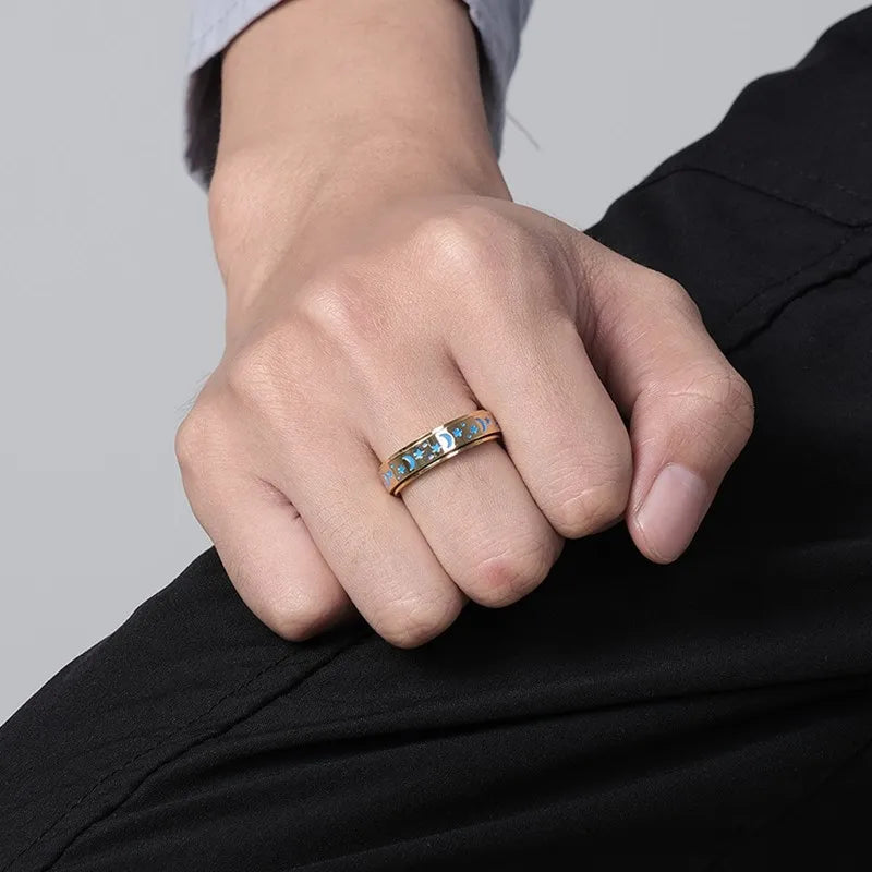 Close-up of a hand wearing a stainless steel star spinner ring with decorative blue accents