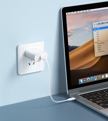 Travel charging cable storage solution with white charger plugged into wall and connected to laptop