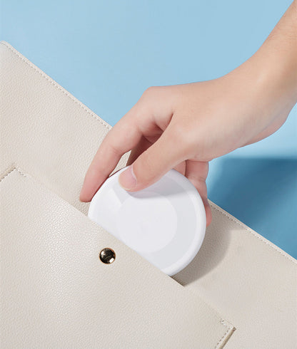 Hand placing white travel charging cable storage solution into beige purse pocket for easy portability