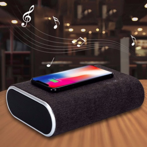 Stylish wireless bluetooth speaker with charger on a wooden table next to a smartphone playing music