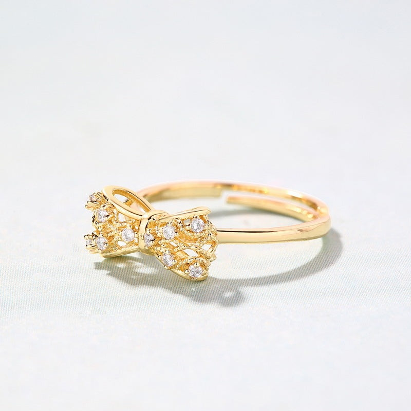 Stylish yellow copper gold-plated women's ring with a bow design and sparkling stones